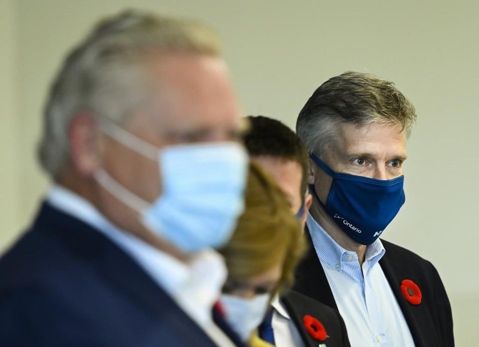 Image shows Premier Ford and Minister Phillips, masked, with two others whose faces are unclear between them.