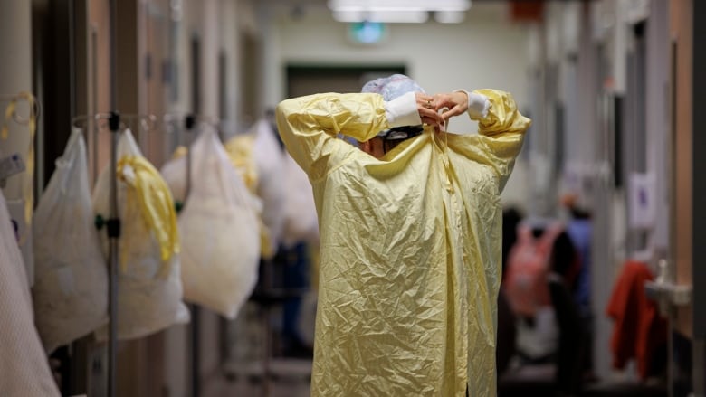 Bill 124, a law passed in 2019, limits wage increases to one per cent per year for Ontario Public Service employees as well as broader public sector workers, including nurses and teachers. (Evan Mitsui/CBC) person putting on a surgical gown
