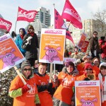 Members outside of Allan Gardens in Toronto, holding up signs that say "CUPE members fight for rights... and won't forget". The sign has a hand-drawn angry pink elephant on it