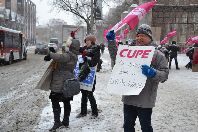 People with CUPE Ontario flags and signs waving at passing traffic
