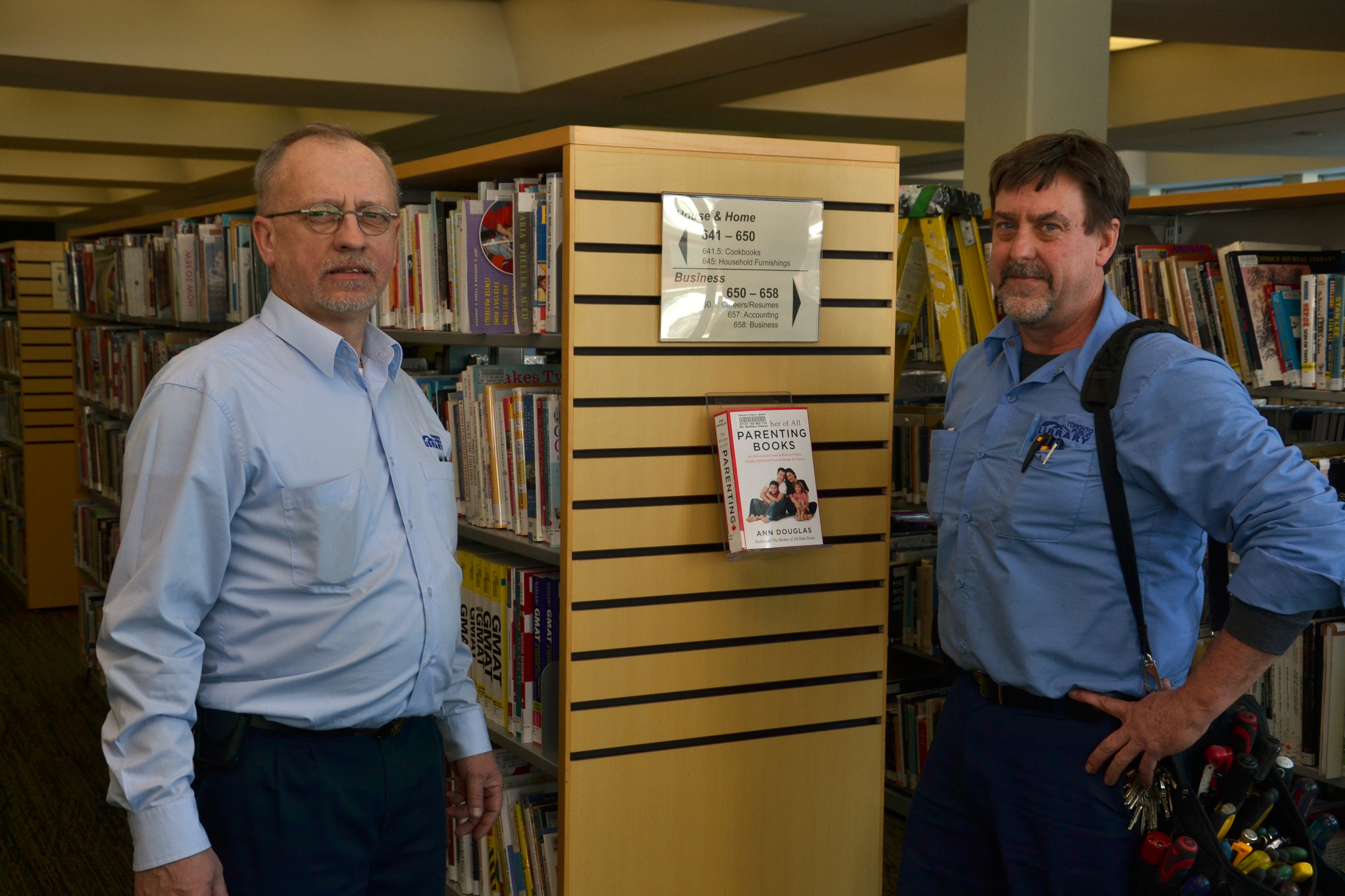Two library workers holding a series of tools