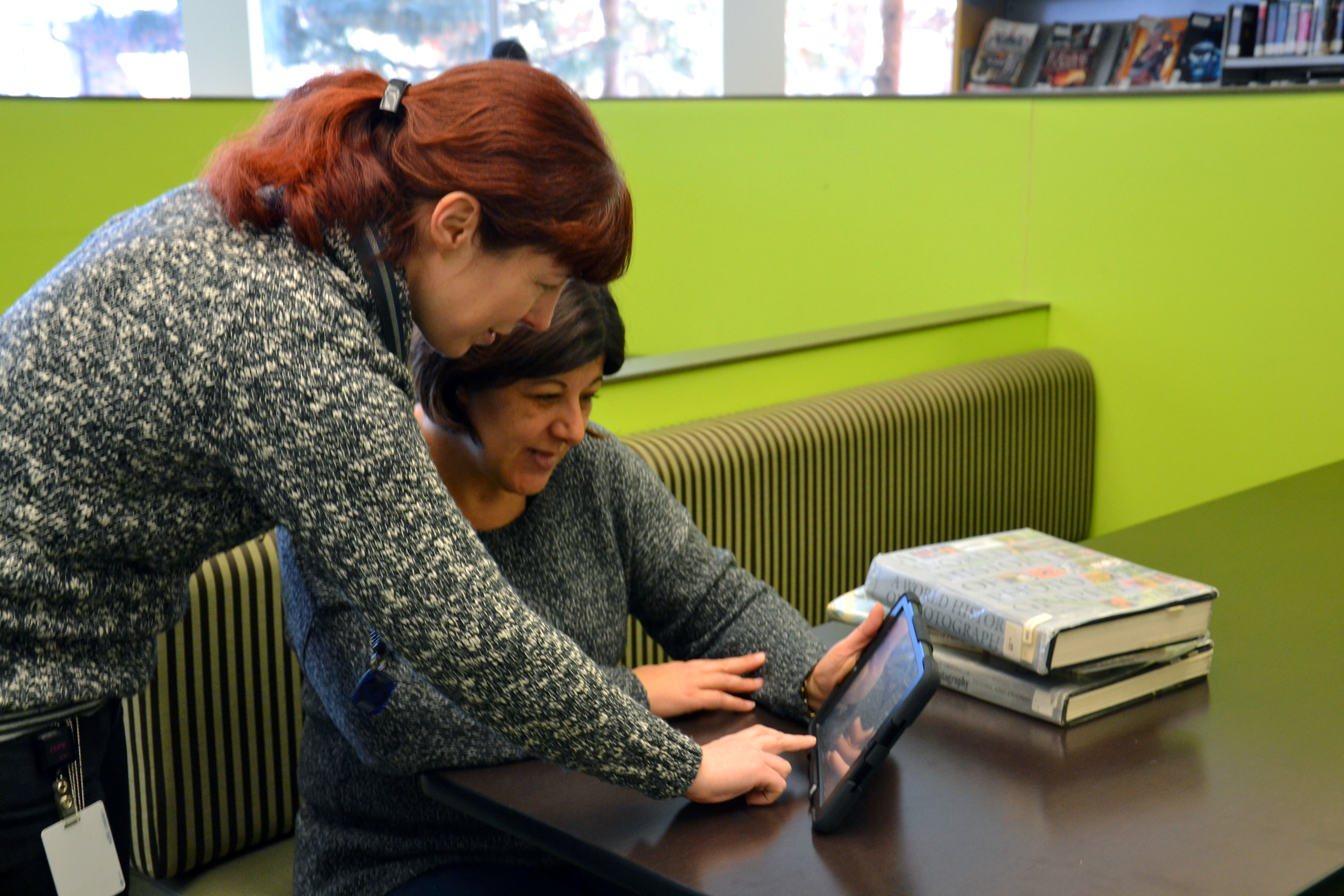 a library worker assists a library patron with using a mobile tablet