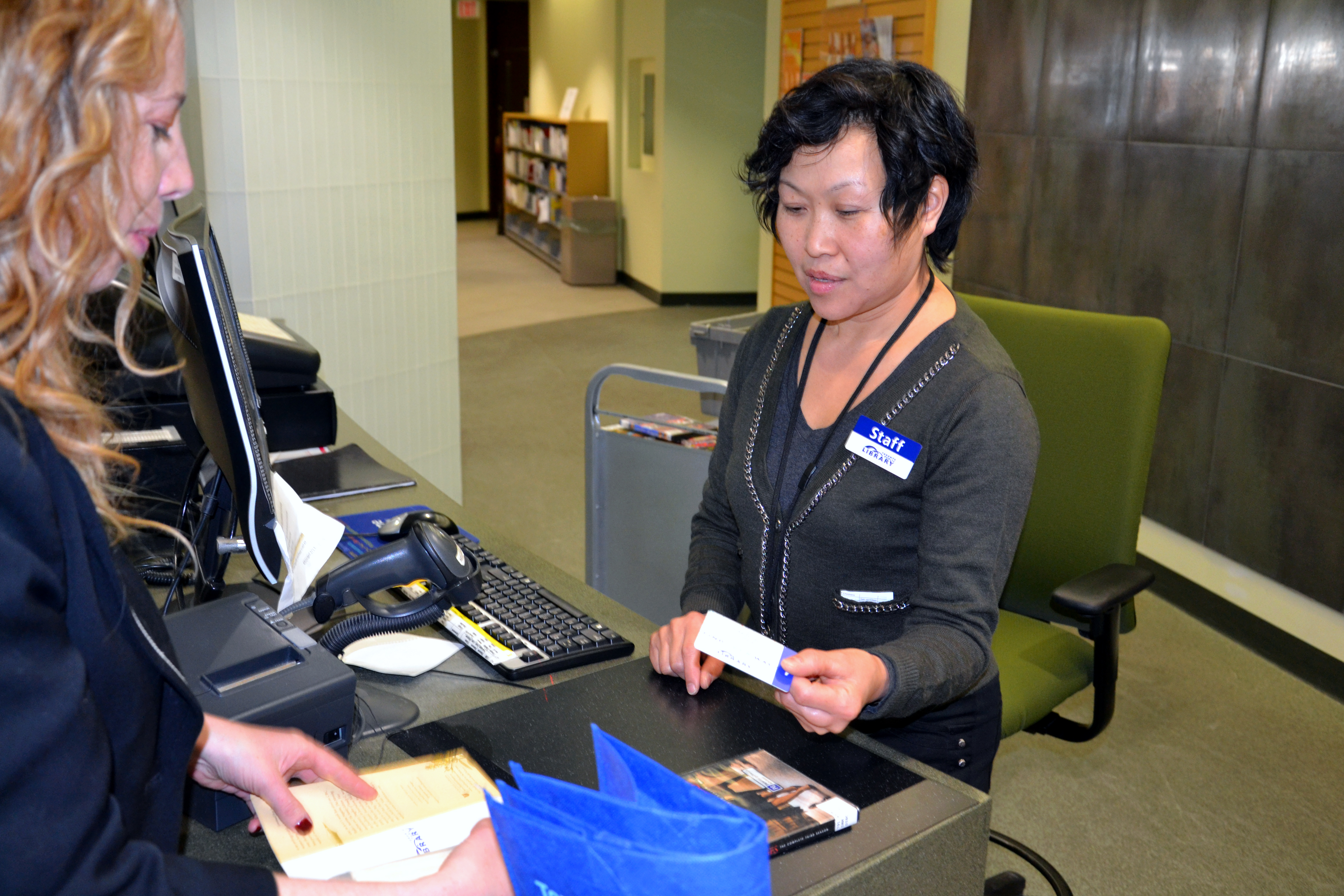 A library worker hands a library card to a library patron