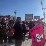 Member holding a CUPE flag facing the camera at a rally
