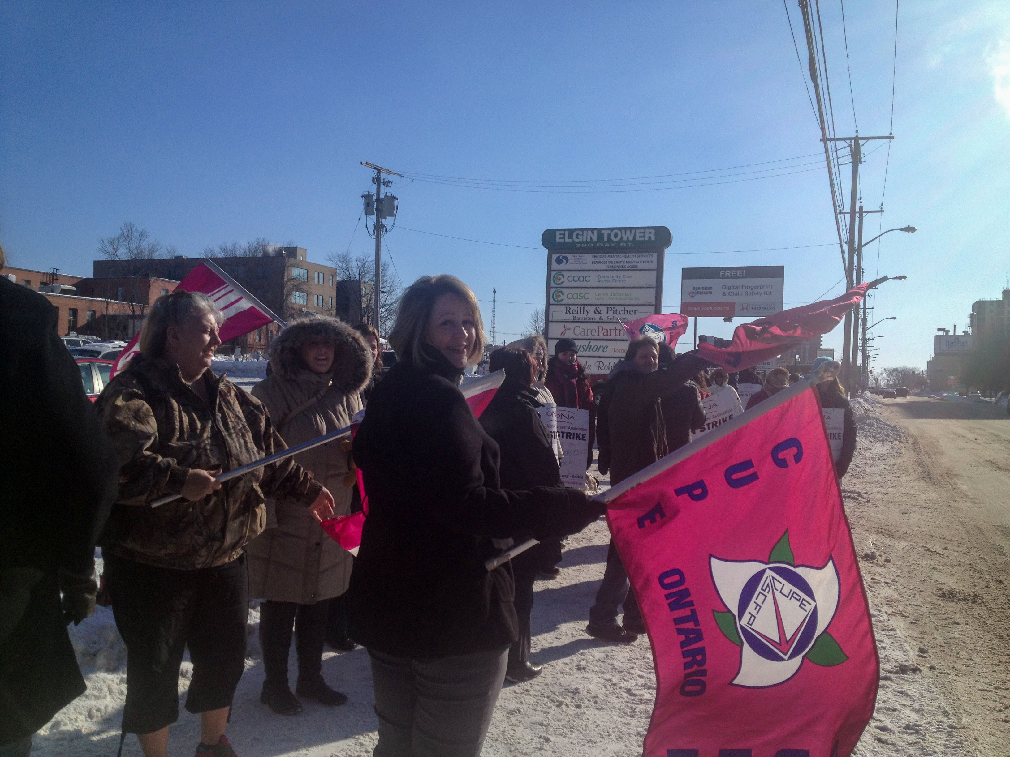 Member holding a CUPE flag facing the camera at a rally