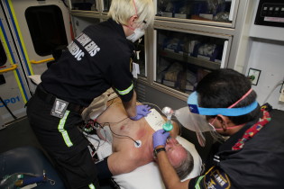 Two paramedics respirate a person on a gurney