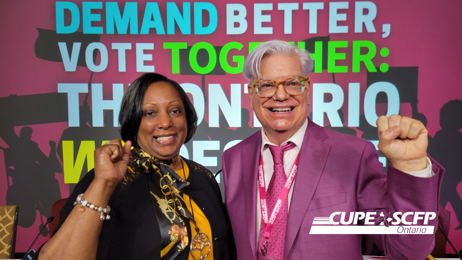 Image shows Yoland and Fred, their hands raised in fists for labour union solidarity, against a backdrop with the CUPE ON Convention 2022 logo in English. It reads 