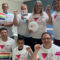 Image shows the Pink Triangle Committee: its members are all making solidarity fists and are holding rainbow flags that read "