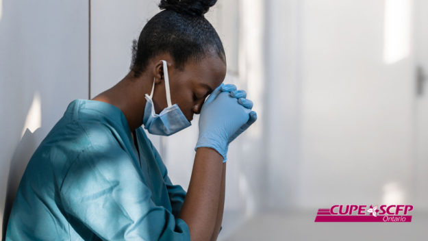 OCHU_24Aug2022 Image shows a healthcare worker, crouched down with their back against a wall and their head on their hands.